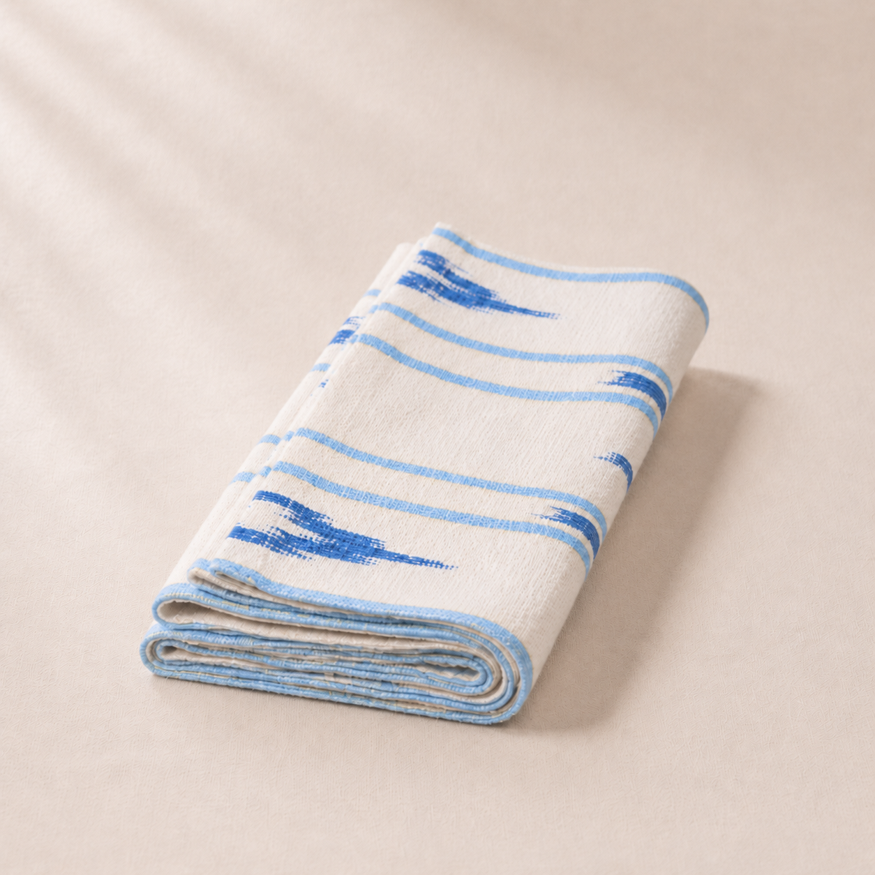 Folded blanket with blue stripes on a beige background