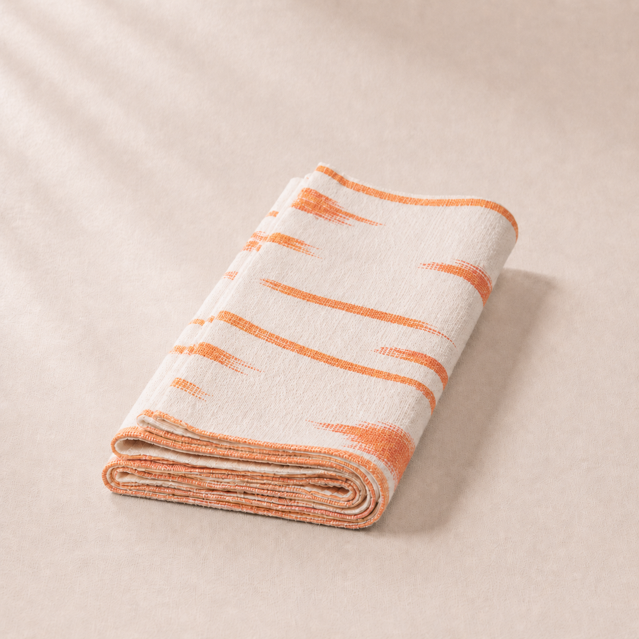 Folded blanket with orange stripes on a beige background