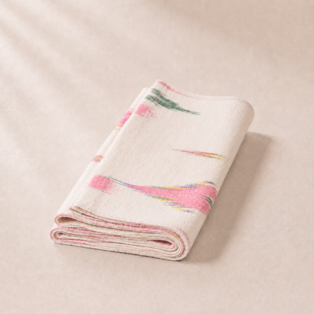Folded blanket with colorful abstract pattern on a beige background