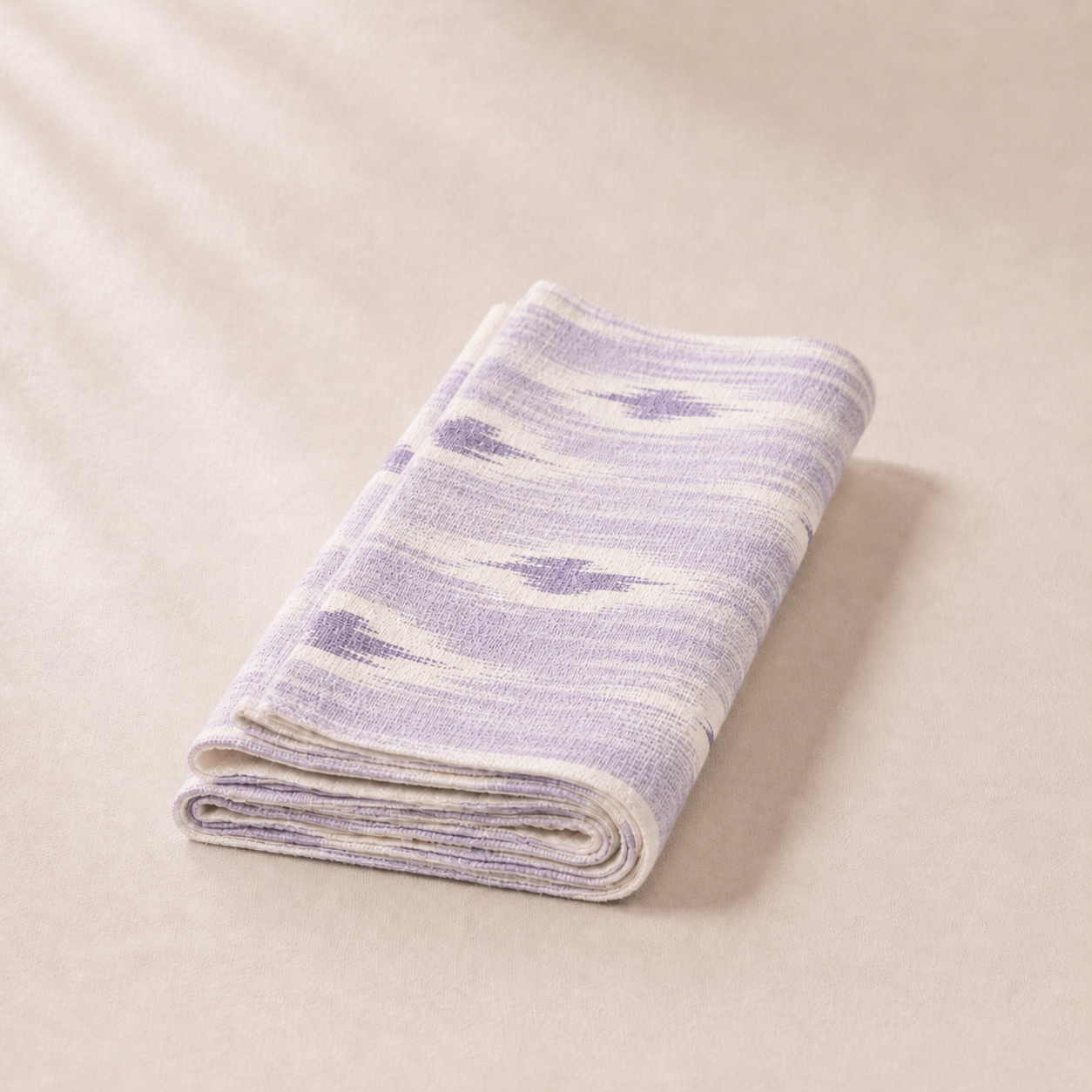 Folded purple and white striped blanket on a beige background