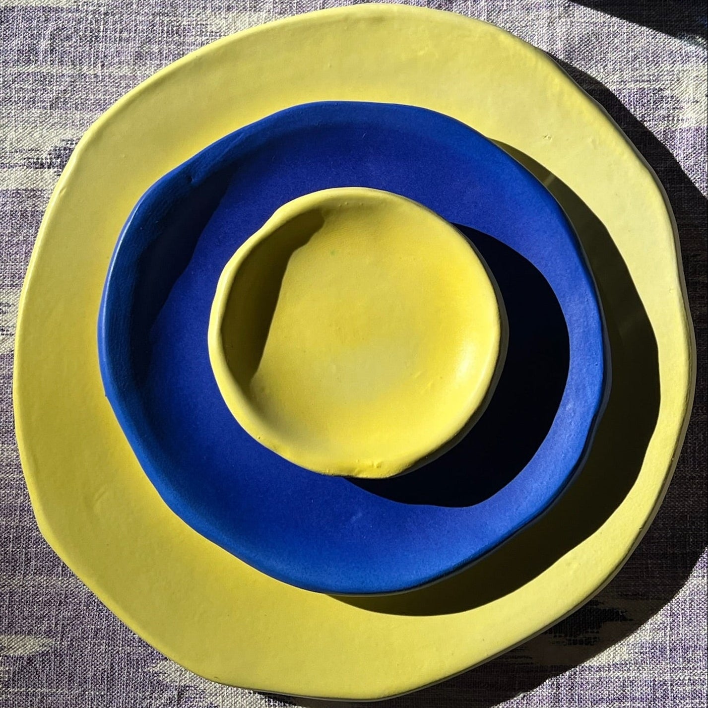 Yellow and blue ceramic bowls stacked on a textured surface