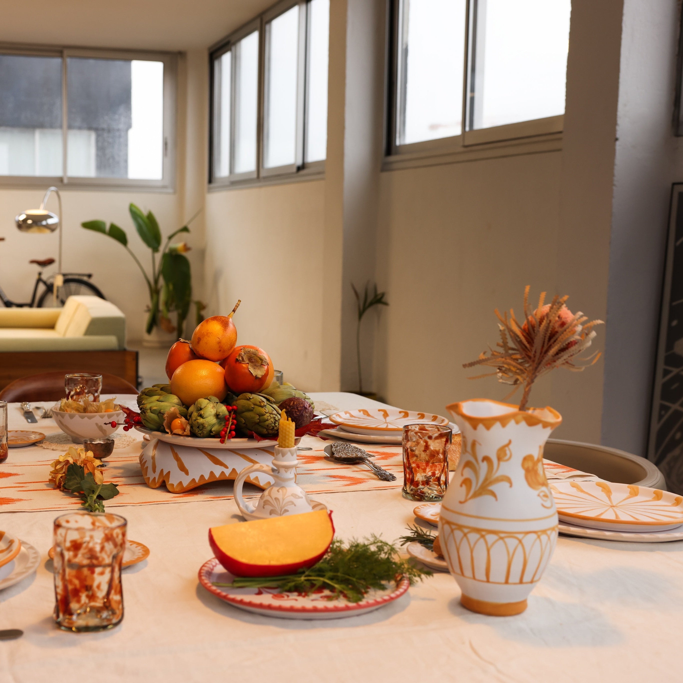 Dining table set with a thanksgiving theme in a room with a bicycle and plants.