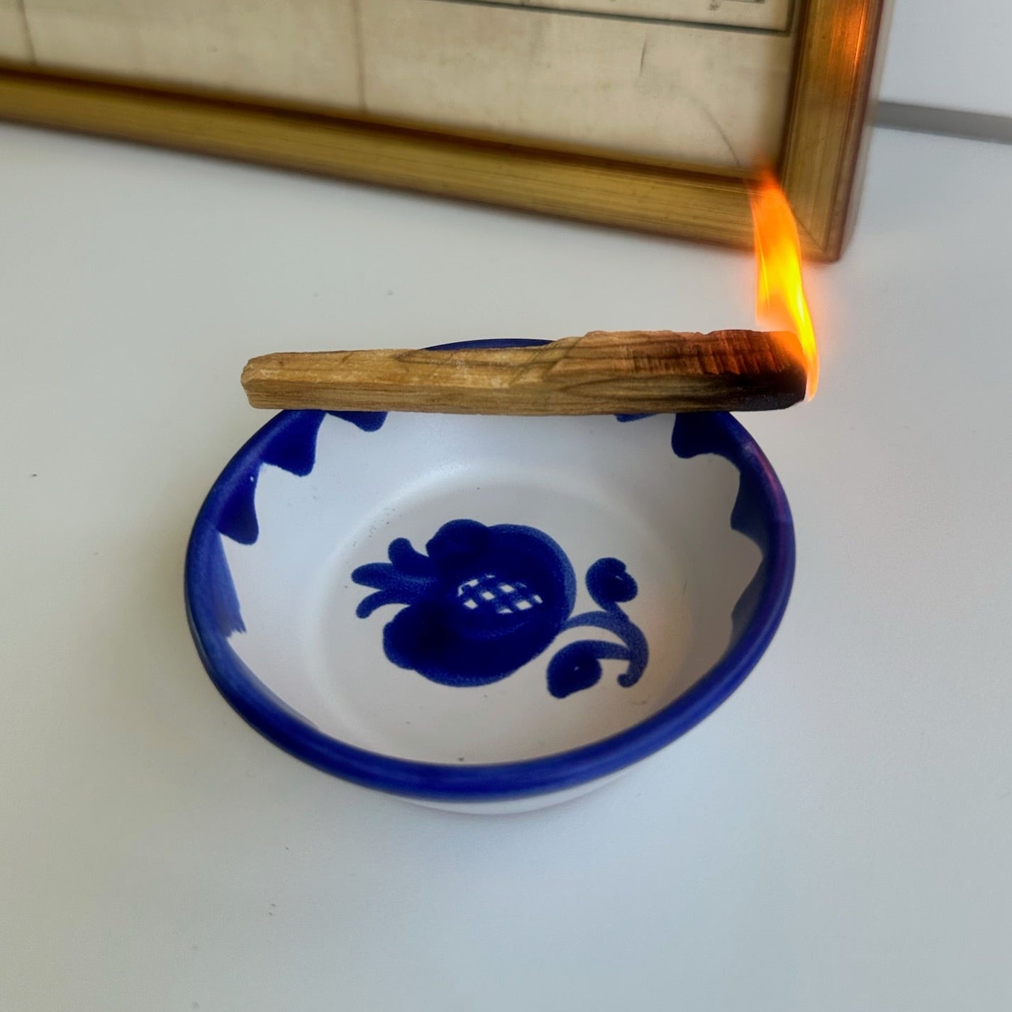 Candle being lit in a blue ceramic dish with an old map in the background
