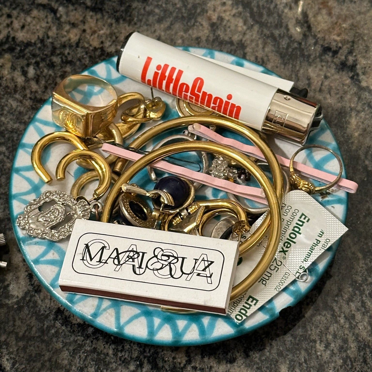Collection of gold keychains on a blue plate with a Littlebrain product in the background. - lifestyle
