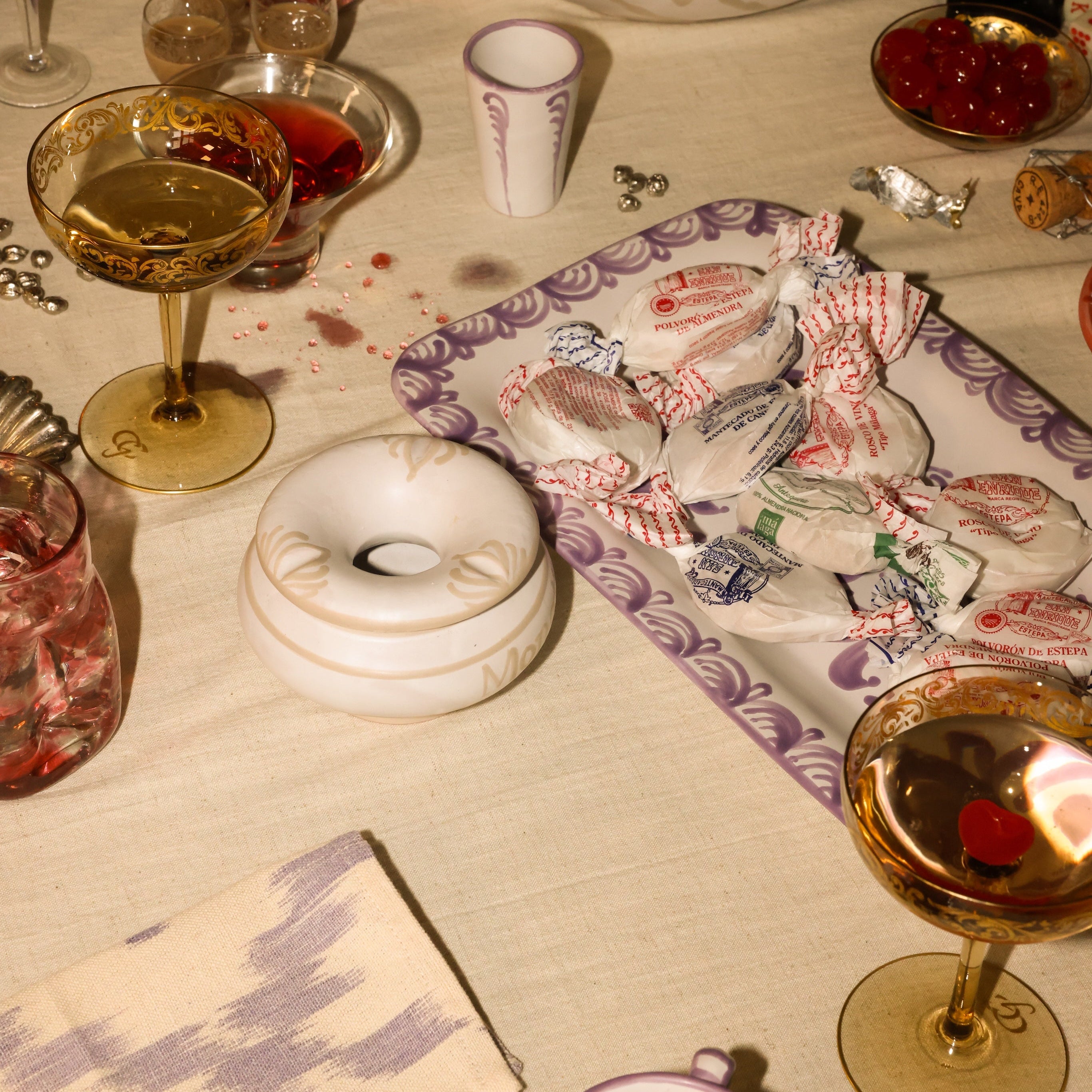 Table setting with wine glasses, a donut, and a box of tissues on a tablecloth. - lifestyle