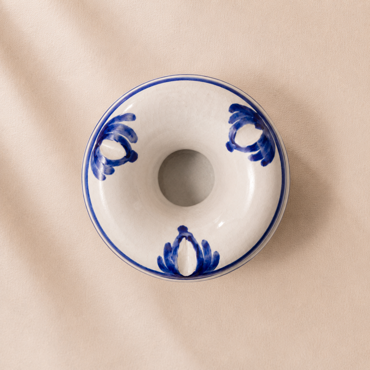 Ceramic donut-shaped dish with blue patterns on a beige background