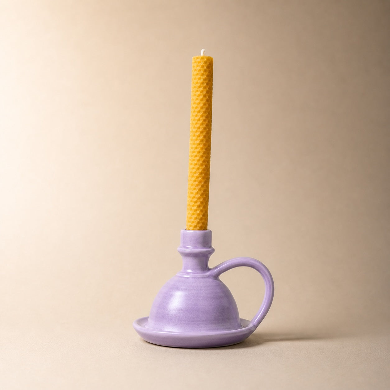 Purple plunger with a yellow candle on a beige background