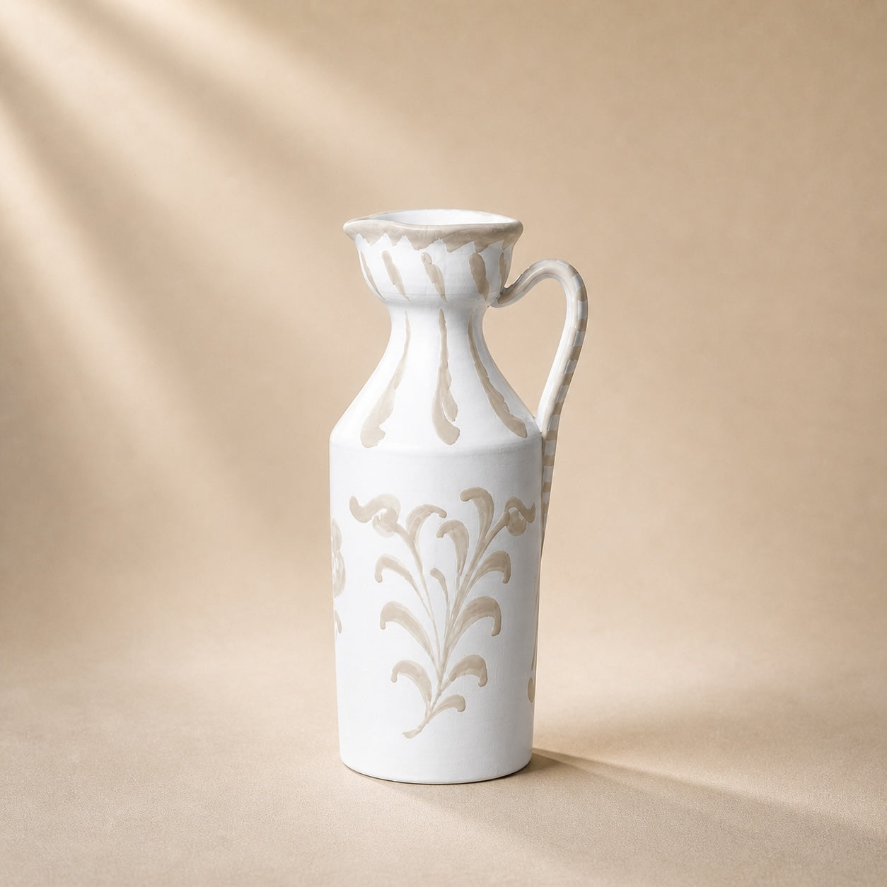 White ceramic pitcher with floral patterns on a beige background