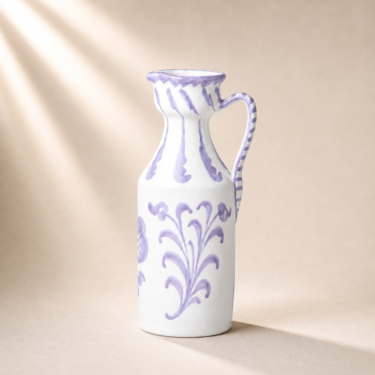 White ceramic pitcher with purple floral patterns on a beige background