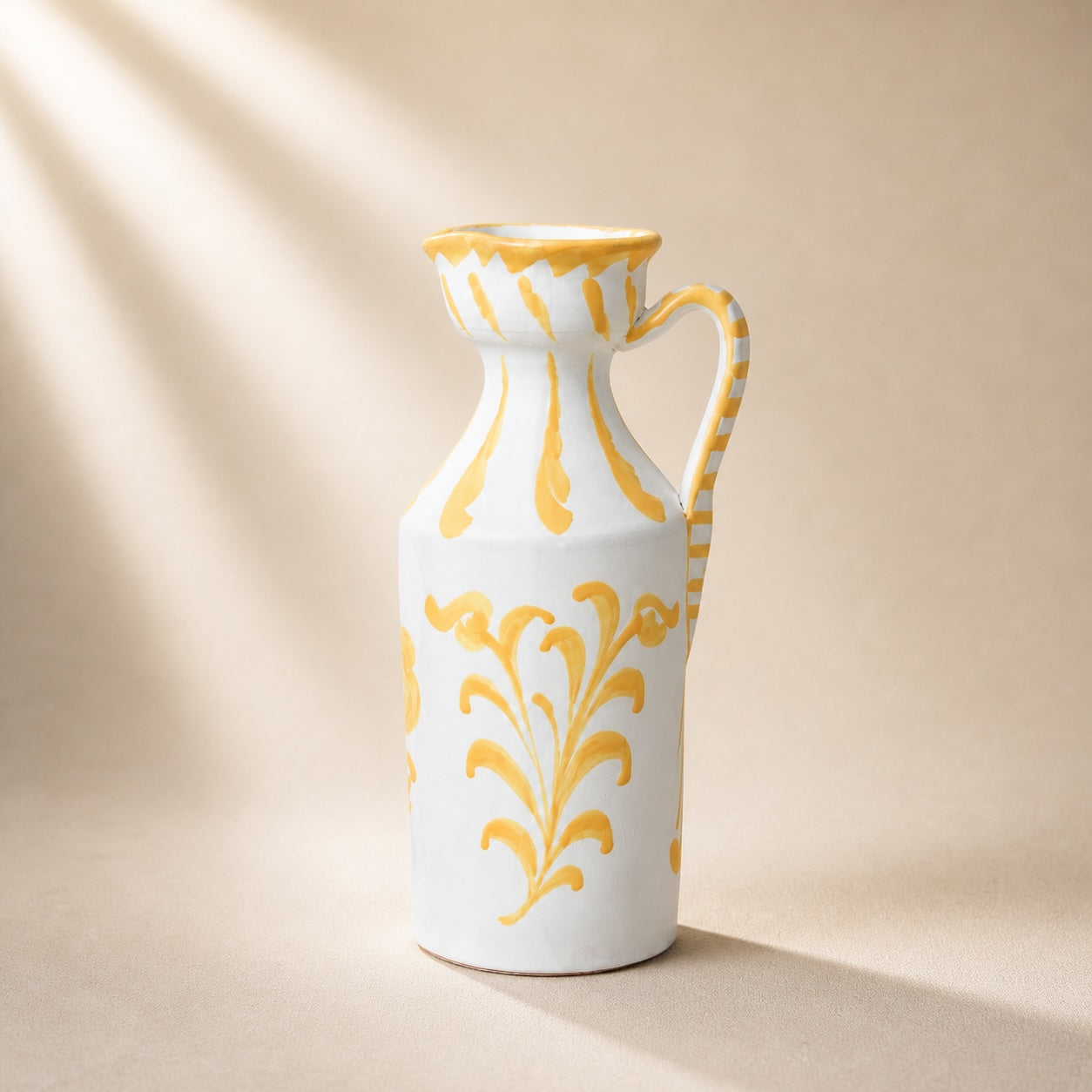 White ceramic pitcher with yellow floral patterns on a beige background