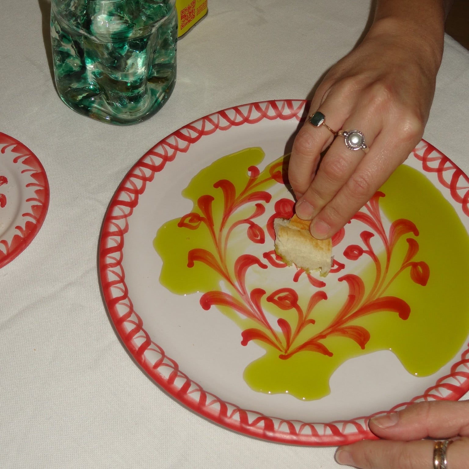 Person eating a piece of cake on a decorative plate with a glass of green liquid and a box in the background. - lifestyle