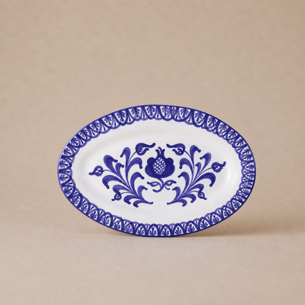 Oval ceramic plate with blue floral design on a beige background