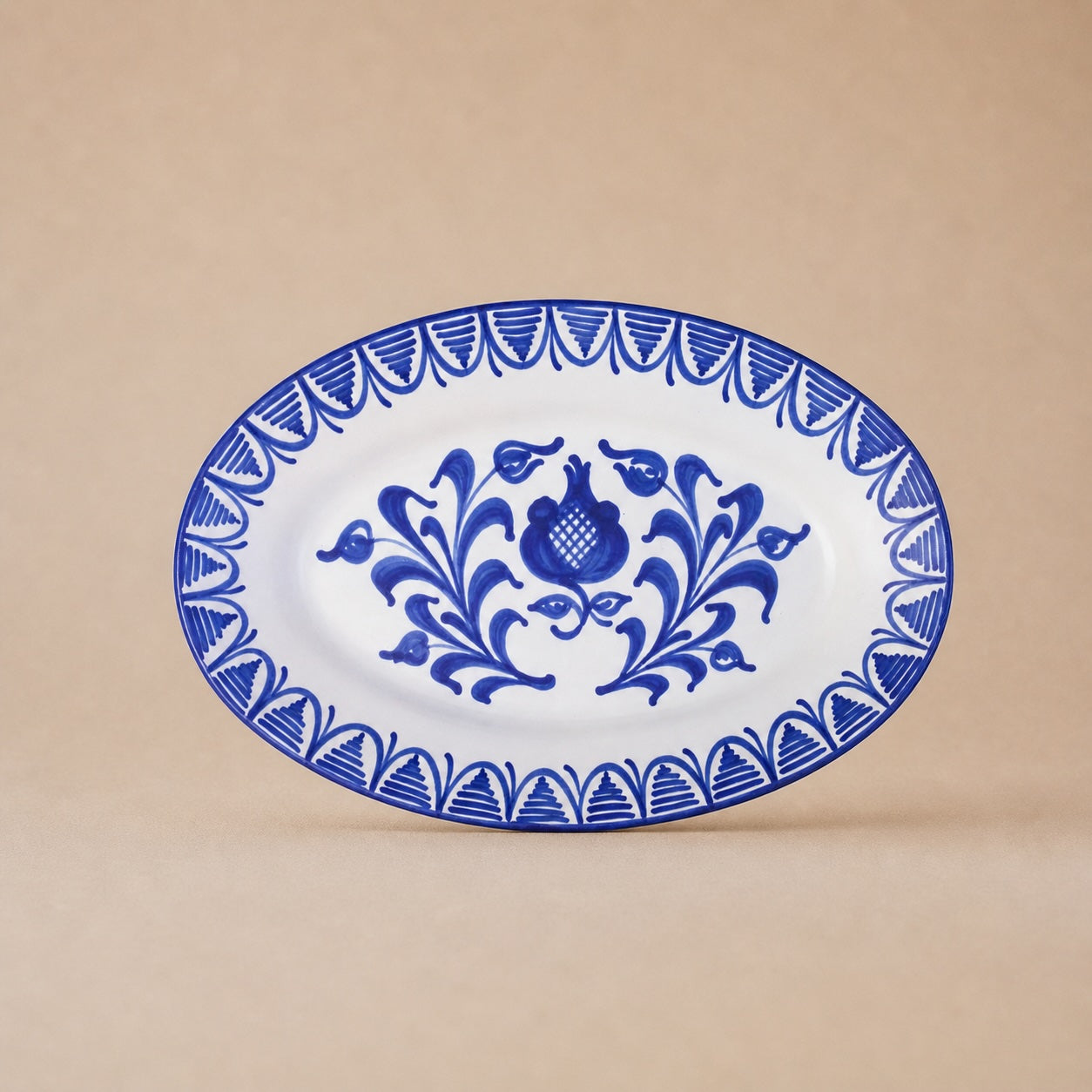 Oval ceramic plate with blue floral design on a beige background