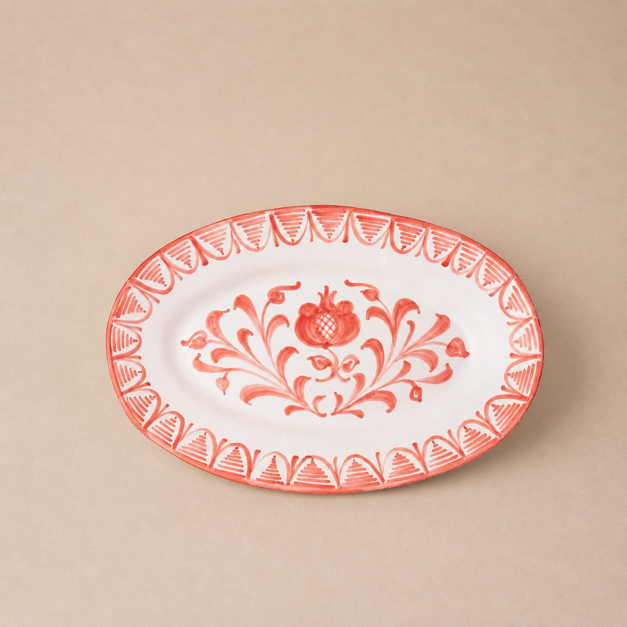 Decorative plate with red floral design on a beige background