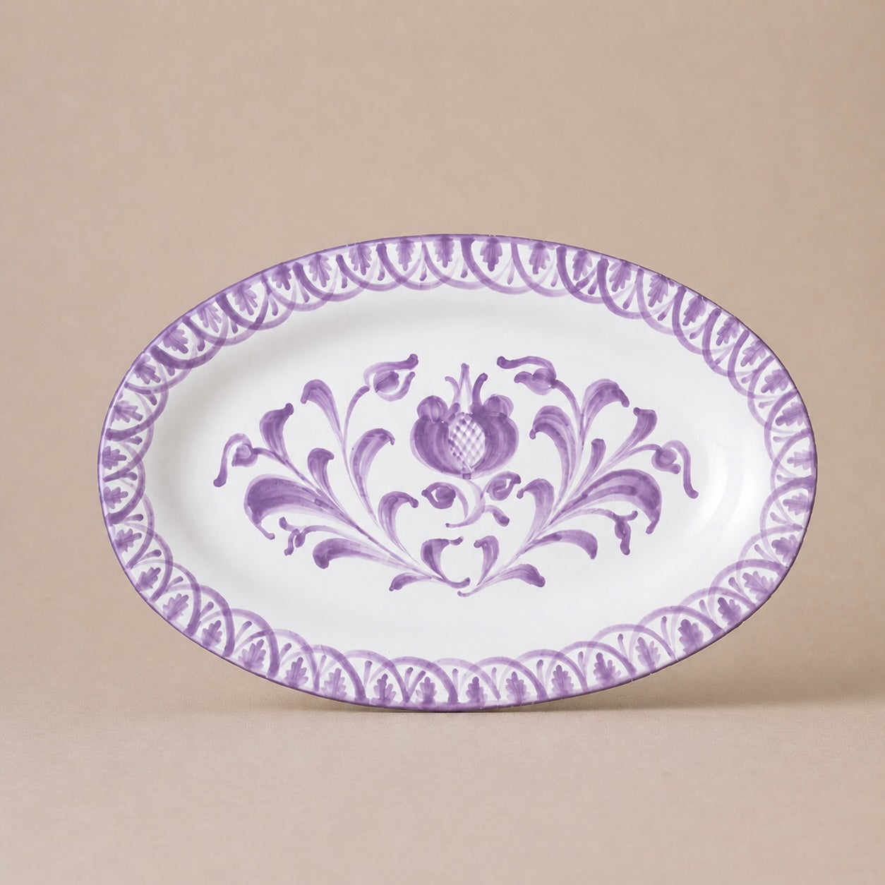 Oval ceramic plate with purple floral design on a beige background