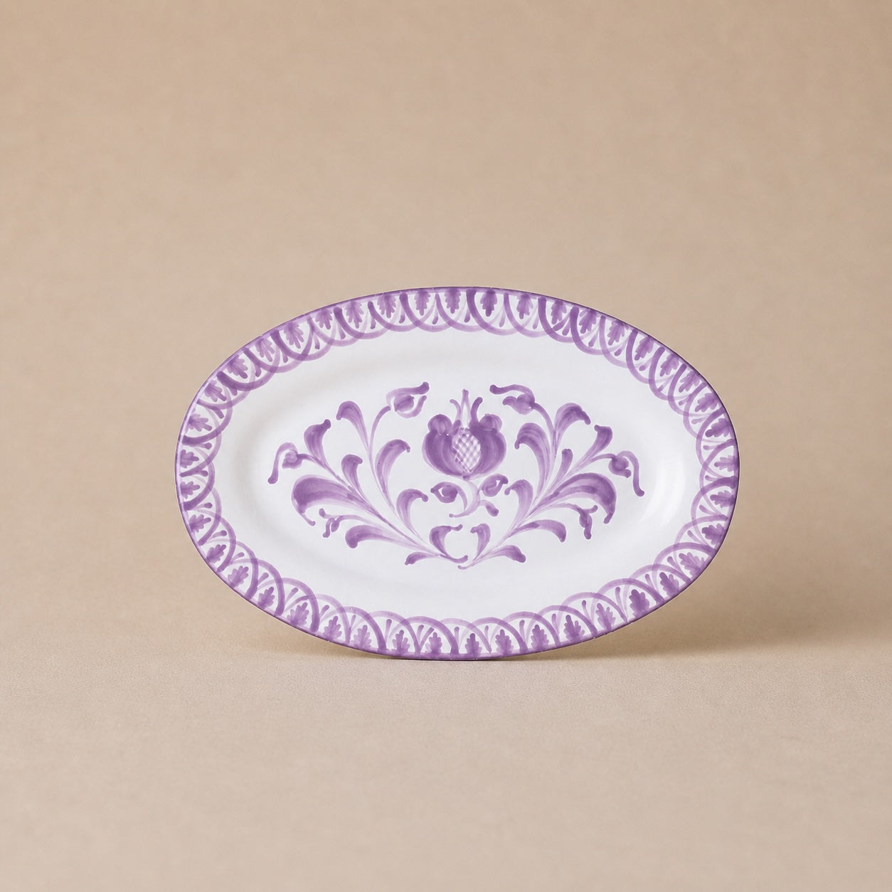 Oval ceramic plate with purple floral pattern on a beige background