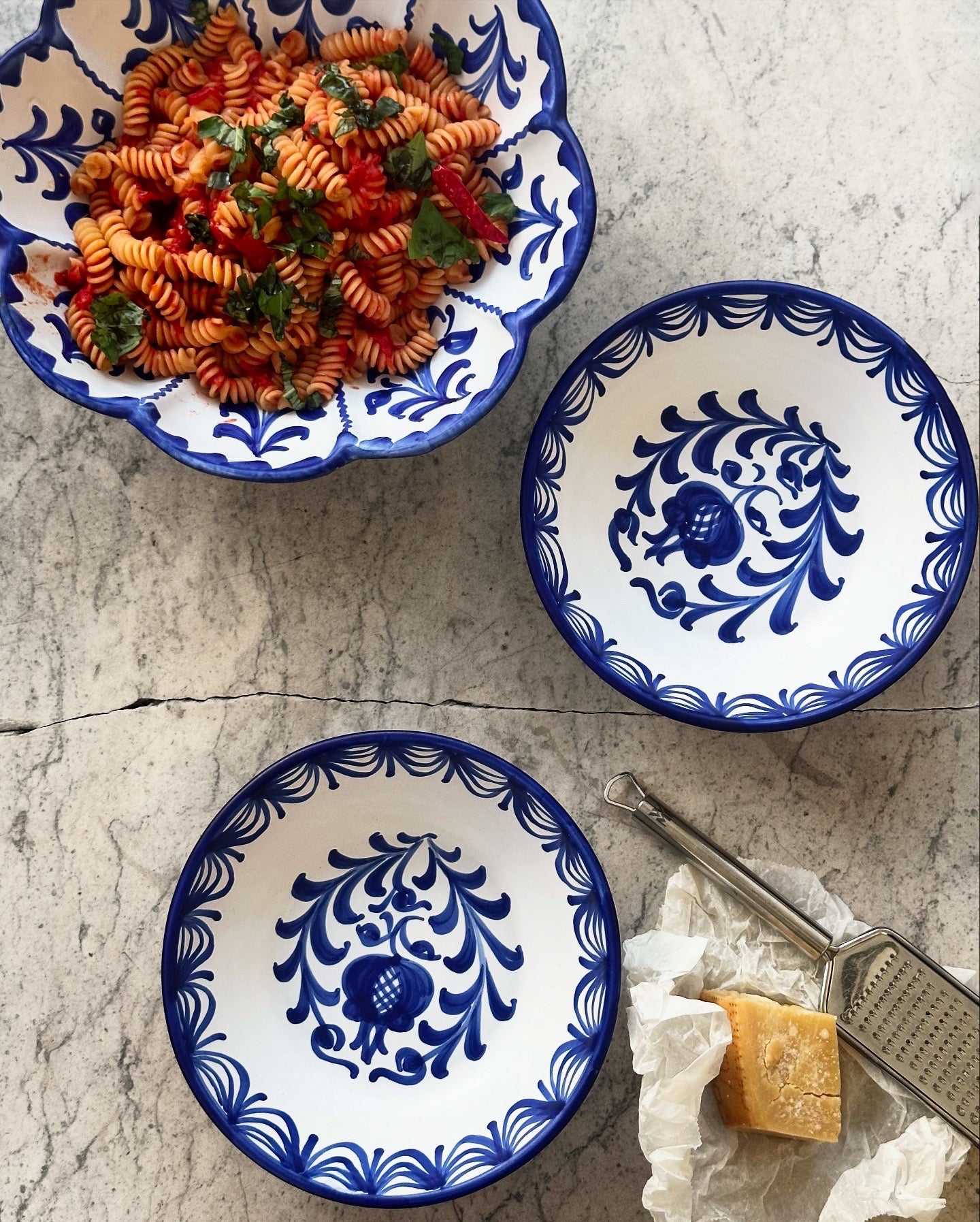 Two blue and white patterned bowls with a dish of pasta on a textured surface.