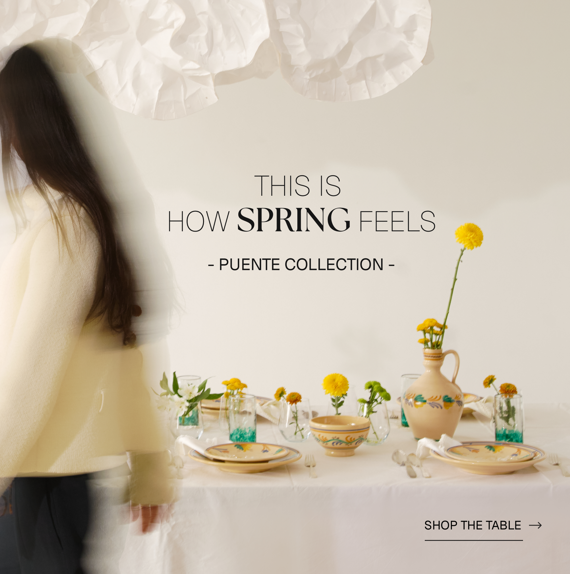 Person looking at a table set with spring-themed decor, featuring flowers and a vase.