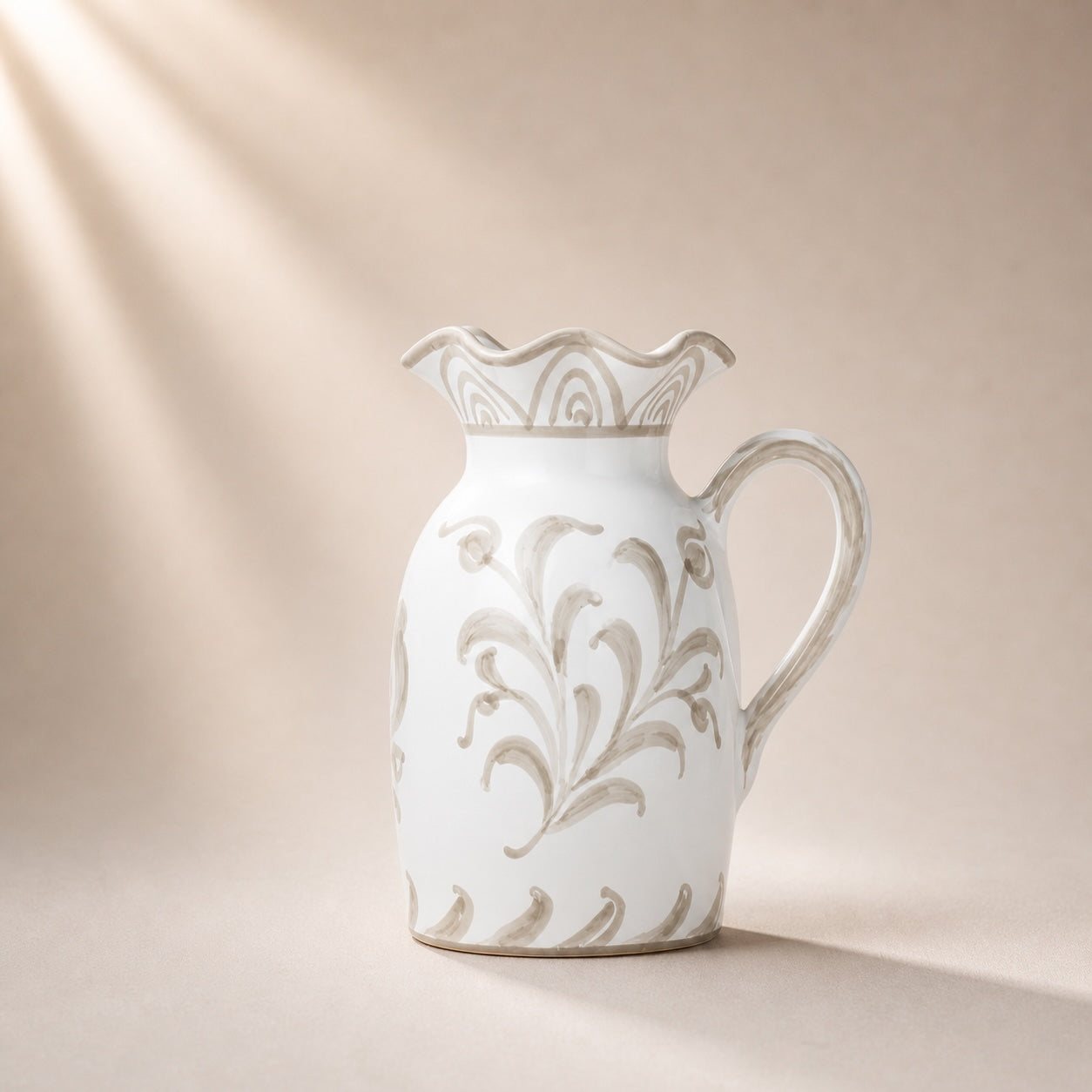 White ceramic pitcher with decorative floral patterns on a beige background