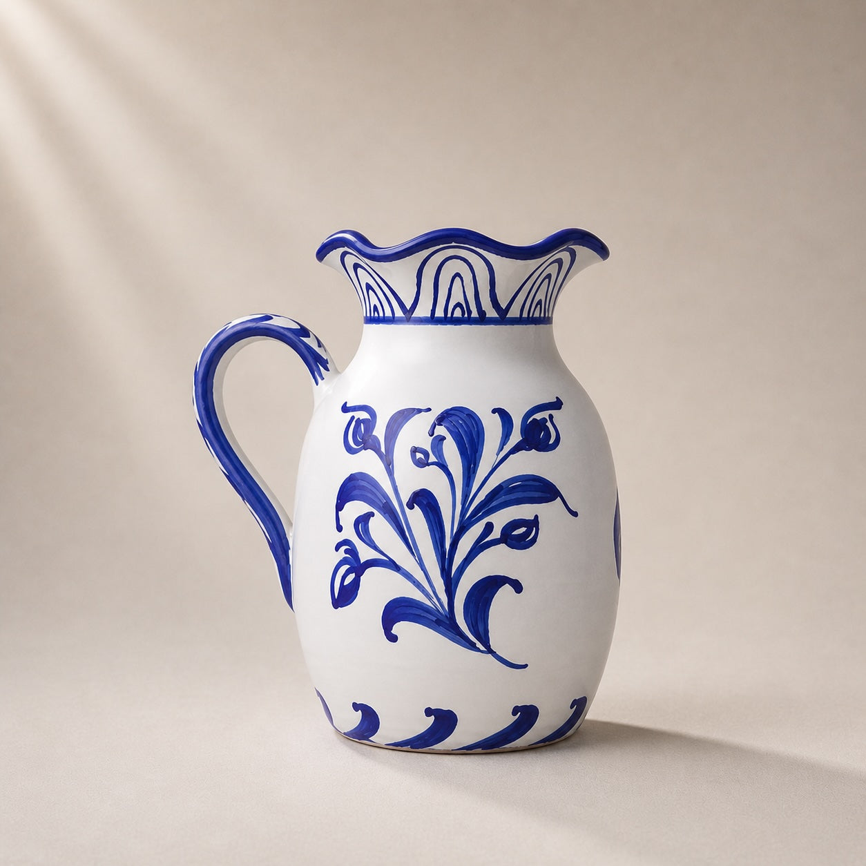 White ceramic pitcher with blue floral patterns on a beige background