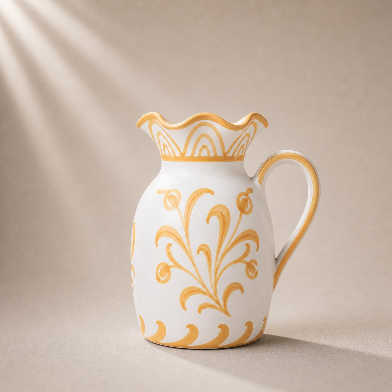 White ceramic pitcher with gold floral patterns on a beige background