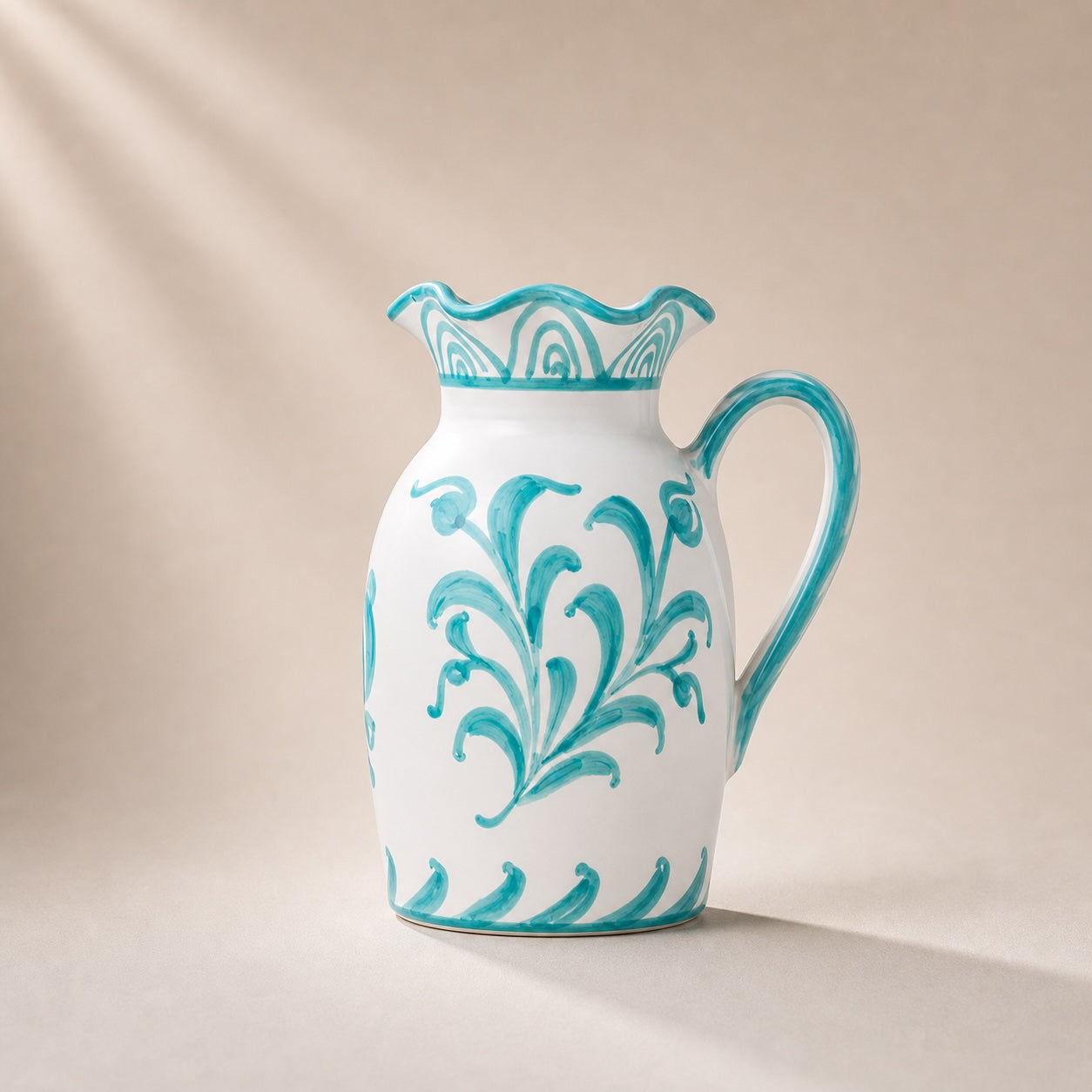 Ceramic pitcher with turquoise floral patterns on a beige background