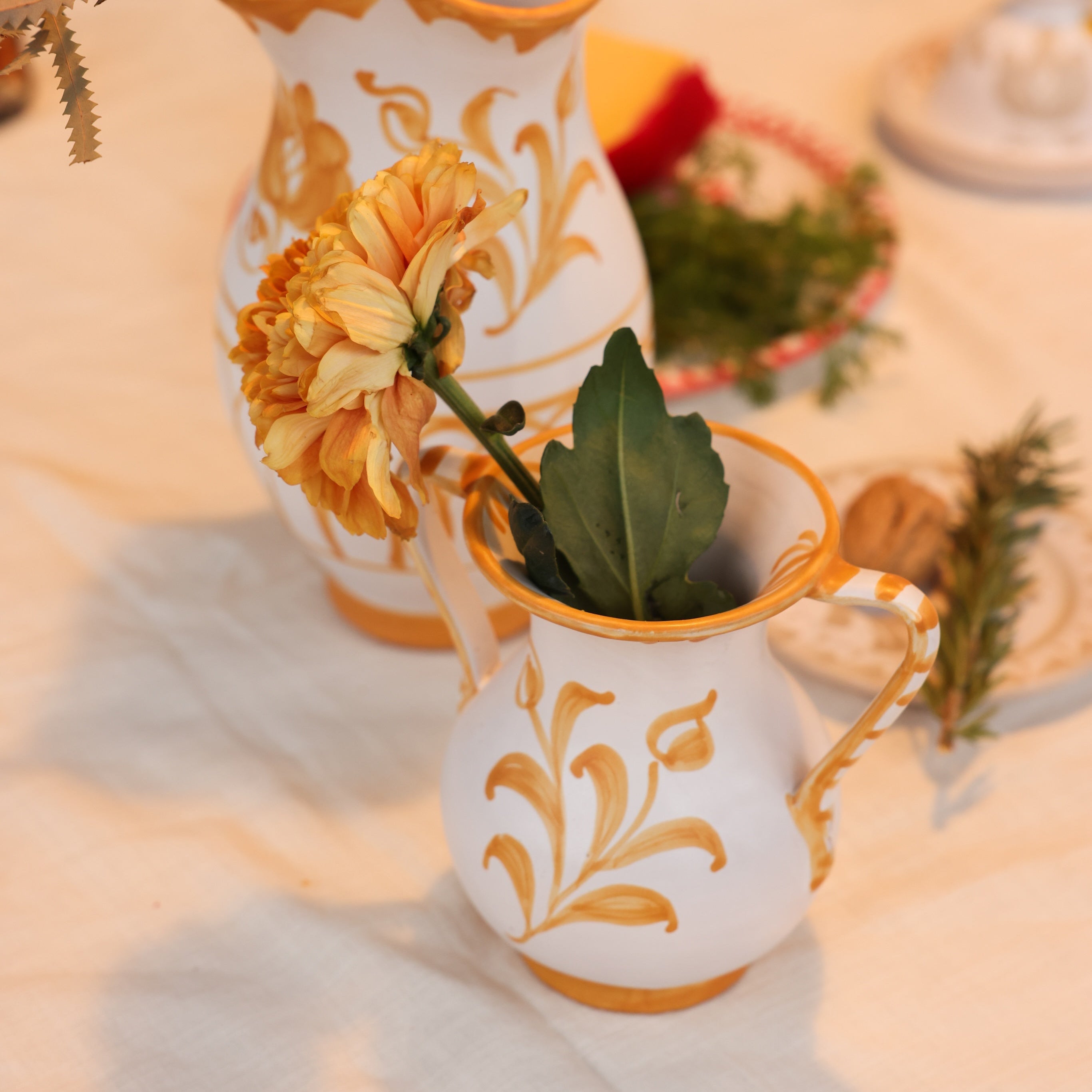 Decorative white vases with gold floral patterns on a table setting. - lifestyle