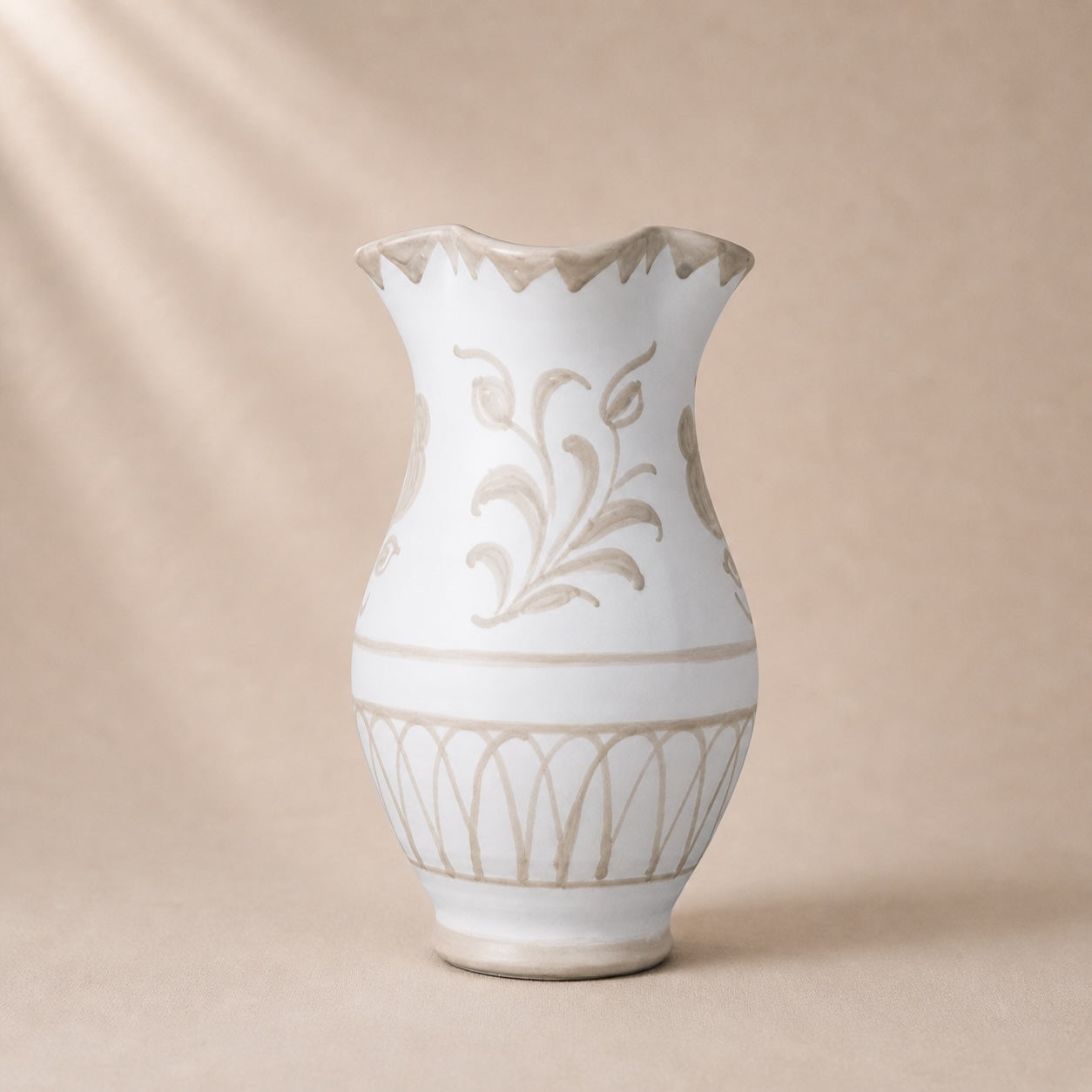 White ceramic vase with beige floral patterns on a beige background