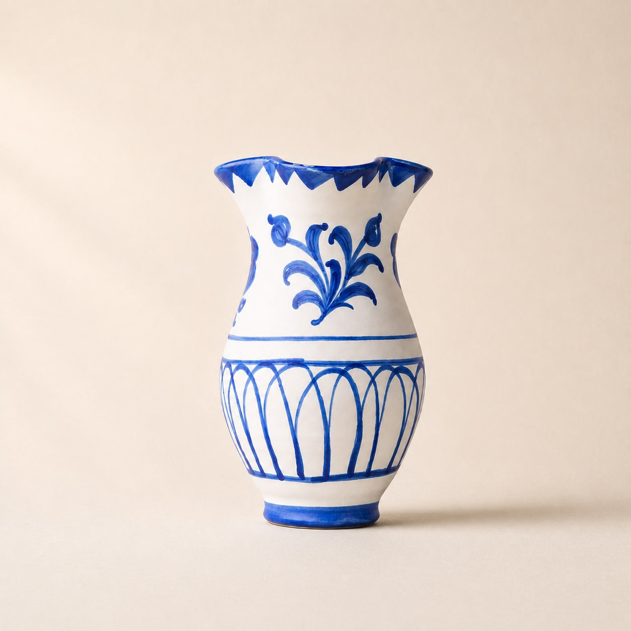 White vase with blue floral and geometric patterns on a beige background