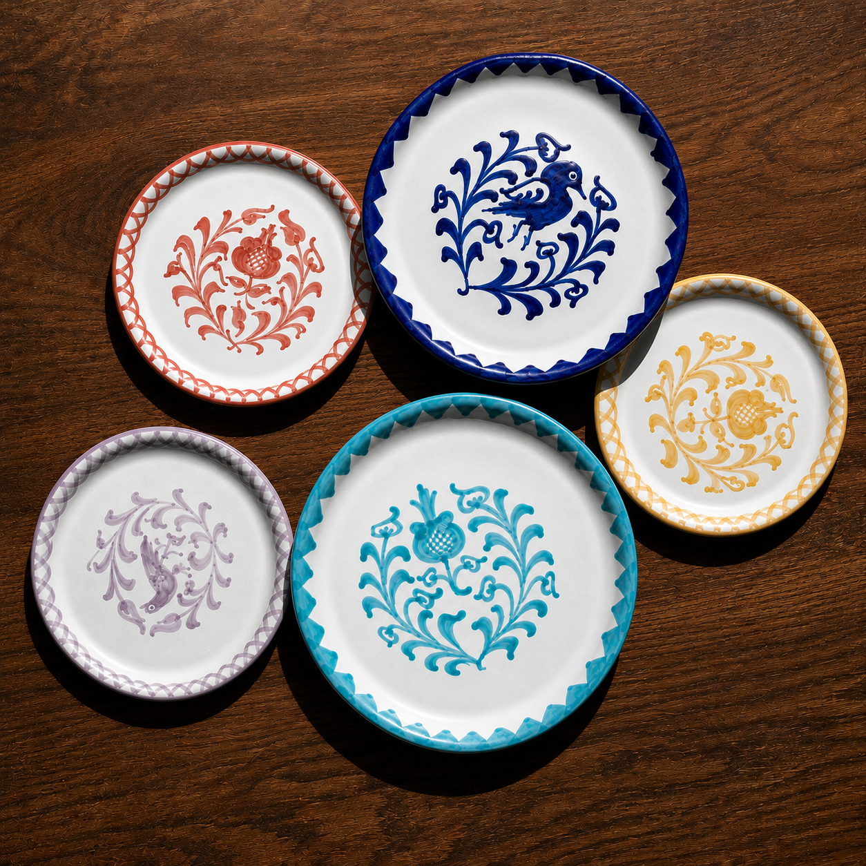 Five decorative ceramic plates with scalloped edges and floral motifs, arranged on a dark wooden surface. The plates feature white backgrounds with blue, red, purple, turquoise, and yellow patterns. - lifestyle