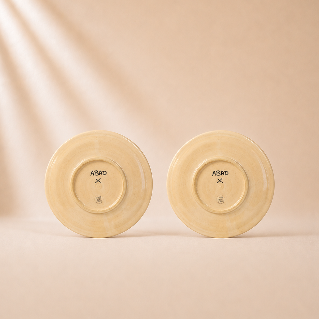 Two beige plates with 'ABAD' branding on a beige background