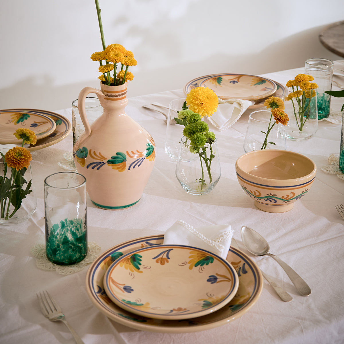 Decorative table setting with ceramic plates, bowls, and vases on a white tablecloth.