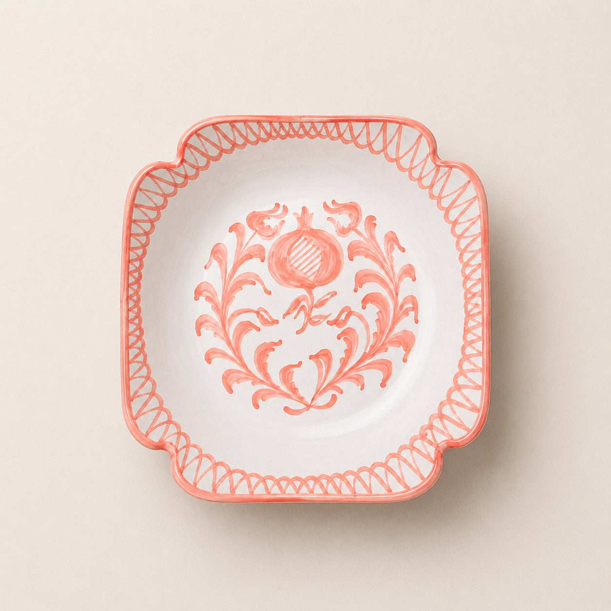 Decorative plate with floral design and coral rim on a beige background