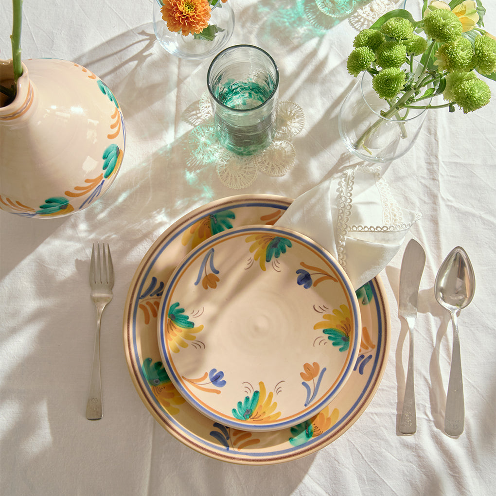 Decorative plate with floral patterns on a table setting with cutlery and vases.