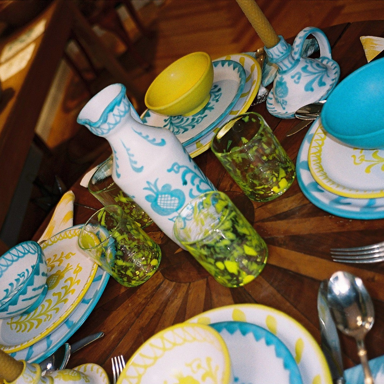 Decorative table setting with patterned plates, glasses, and a bottle on a wooden table. - lifestyle
