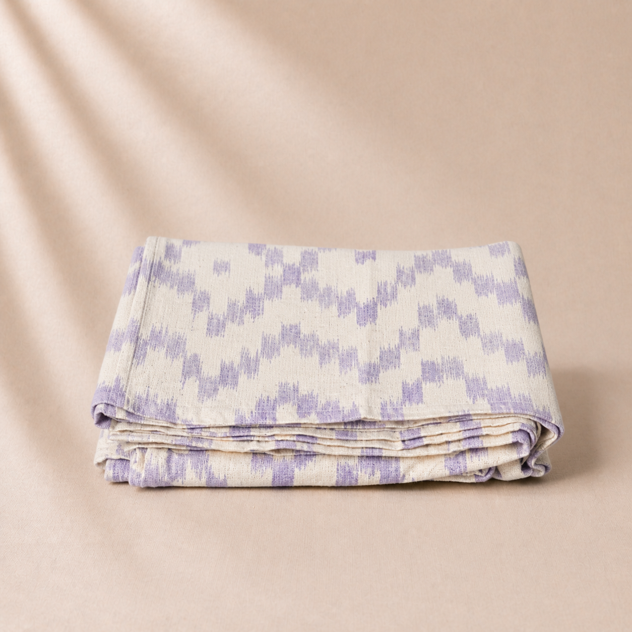 Folded fabric with purple and white pattern on a beige background