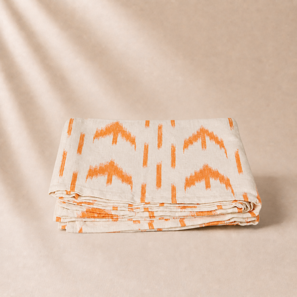 Folded fabric with orange pattern on a beige background
