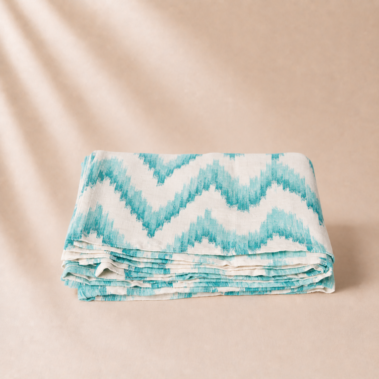 Folded blanket with blue and white zigzag pattern on a beige background