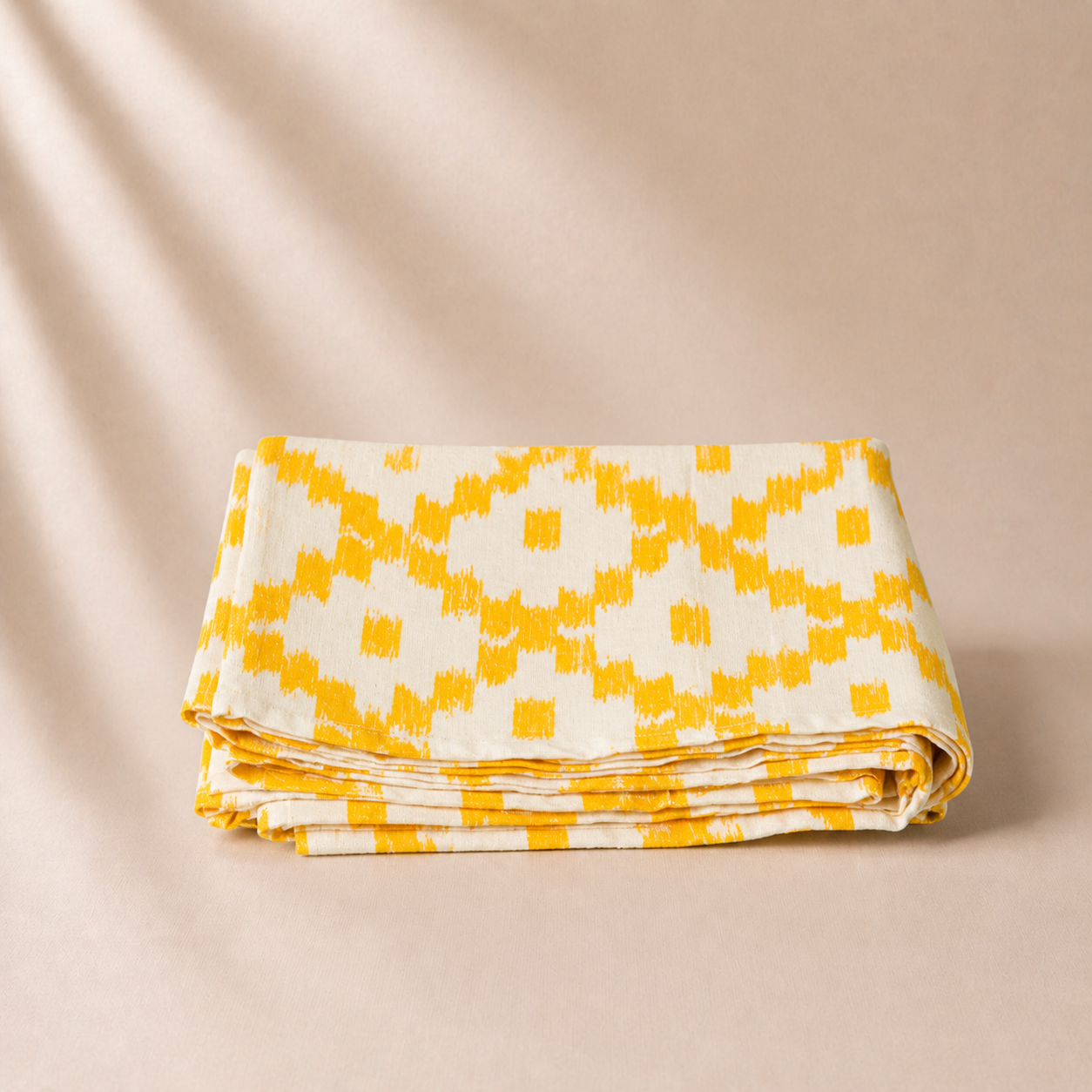 Folded fabric with yellow and white geometric pattern on a beige background