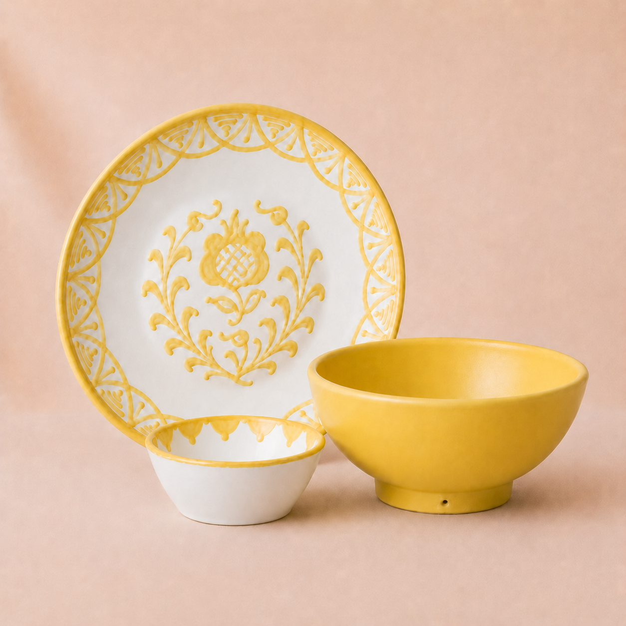 Ceramic plate, bowl, and saucer with yellow floral design on a beige background