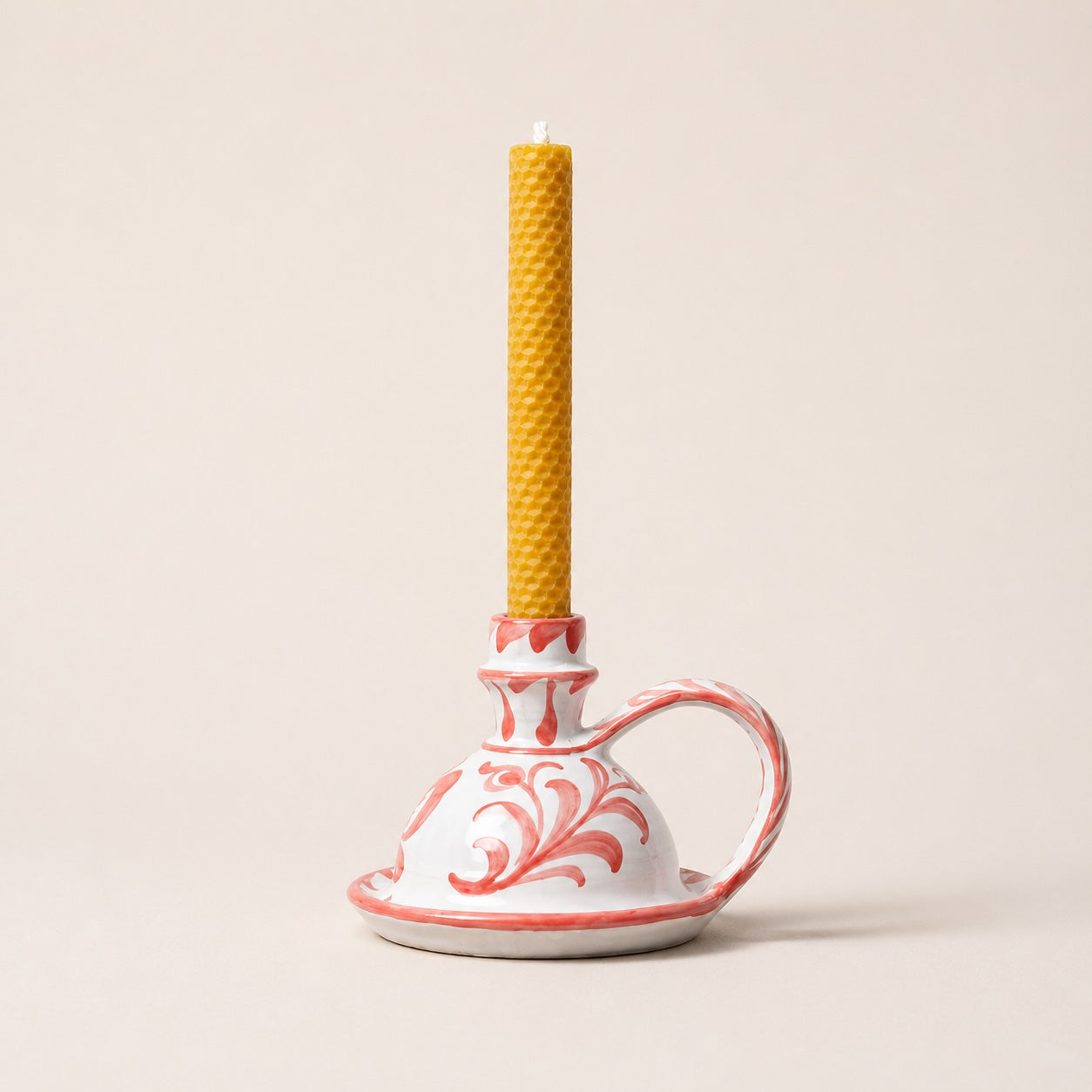 Decorative ceramic holder with a yellow candle on a beige background