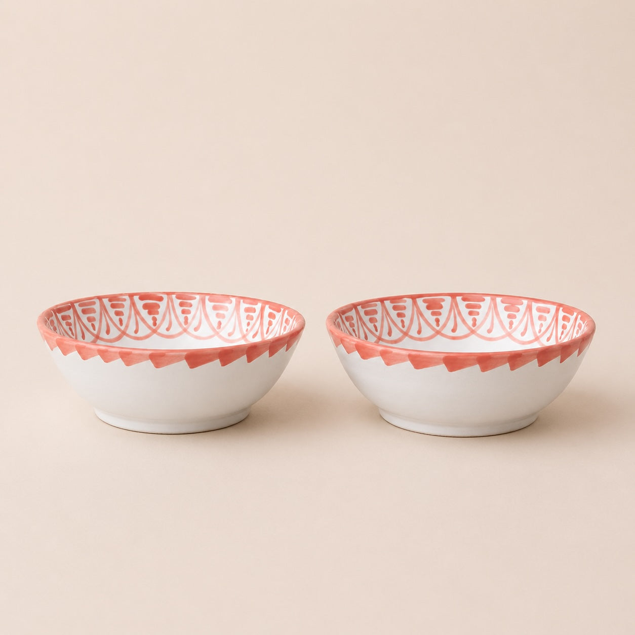 Two ceramic bowls with red decorative rims on a beige background