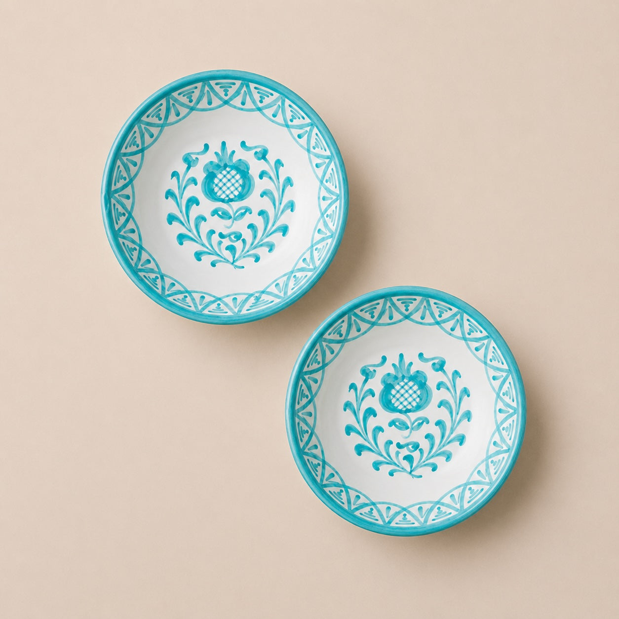 Two turquoise and white decorative plates on a beige background