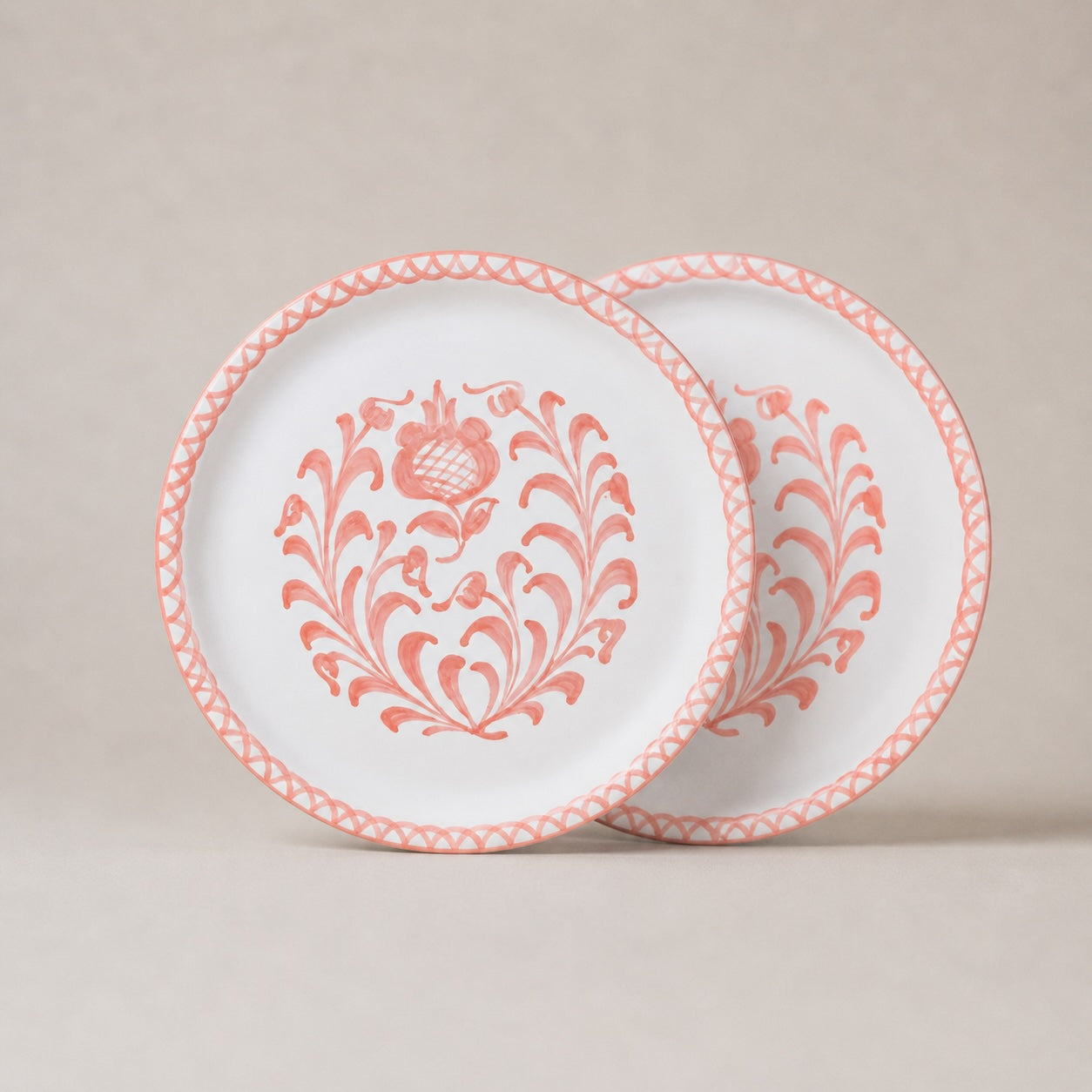 Two ceramic plates with pink floral patterns on a beige background