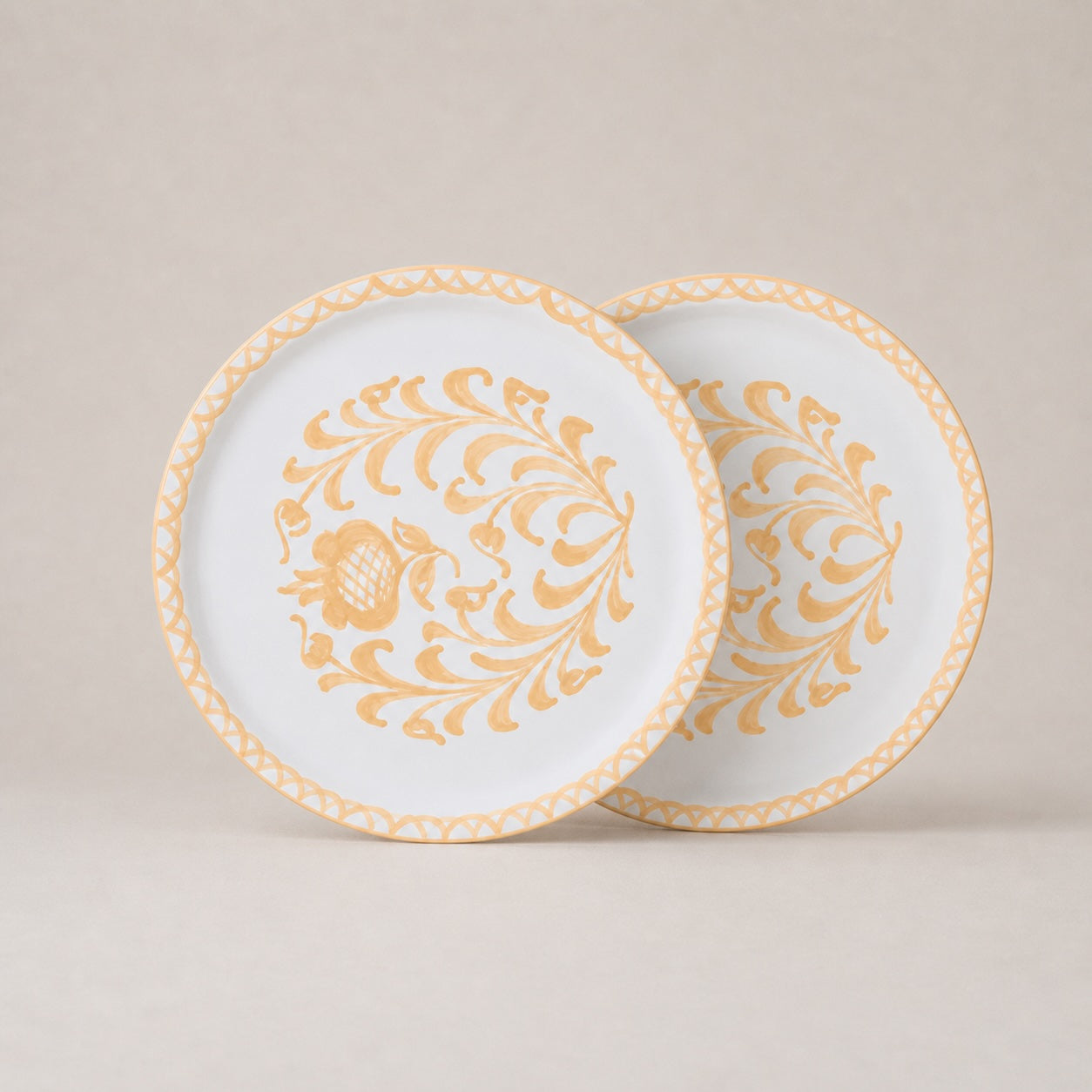 Two decorative plates with gold floral patterns on a beige background