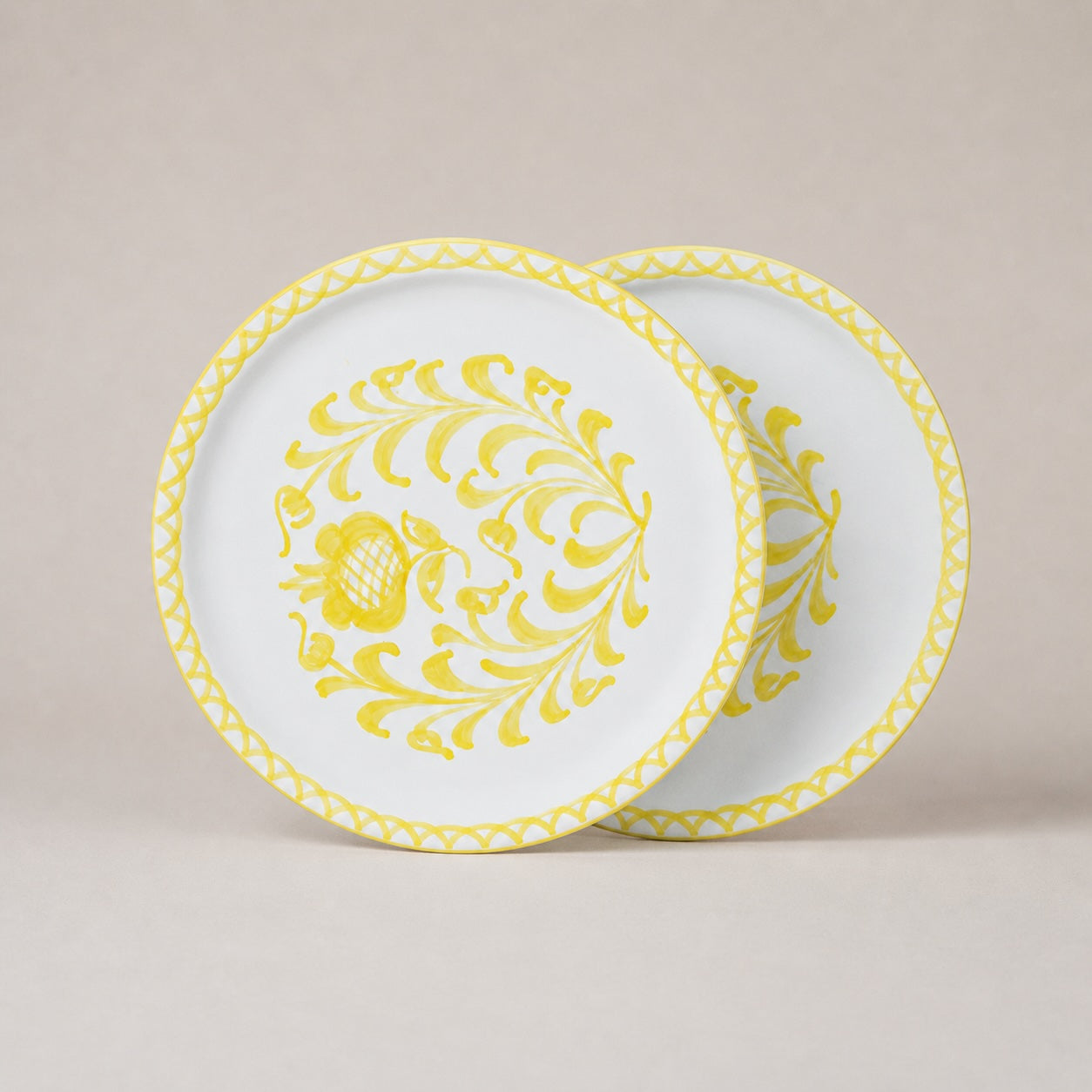 Two white plates with yellow floral patterns on a beige background