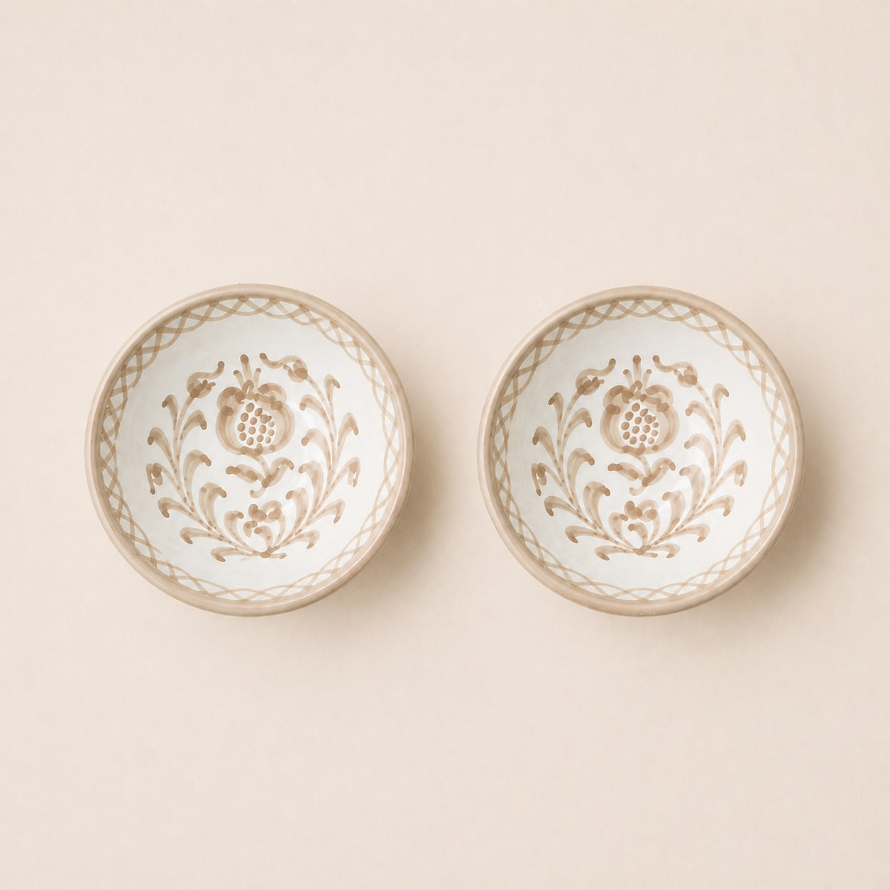 Two decorative ceramic bowls with floral patterns on a beige background