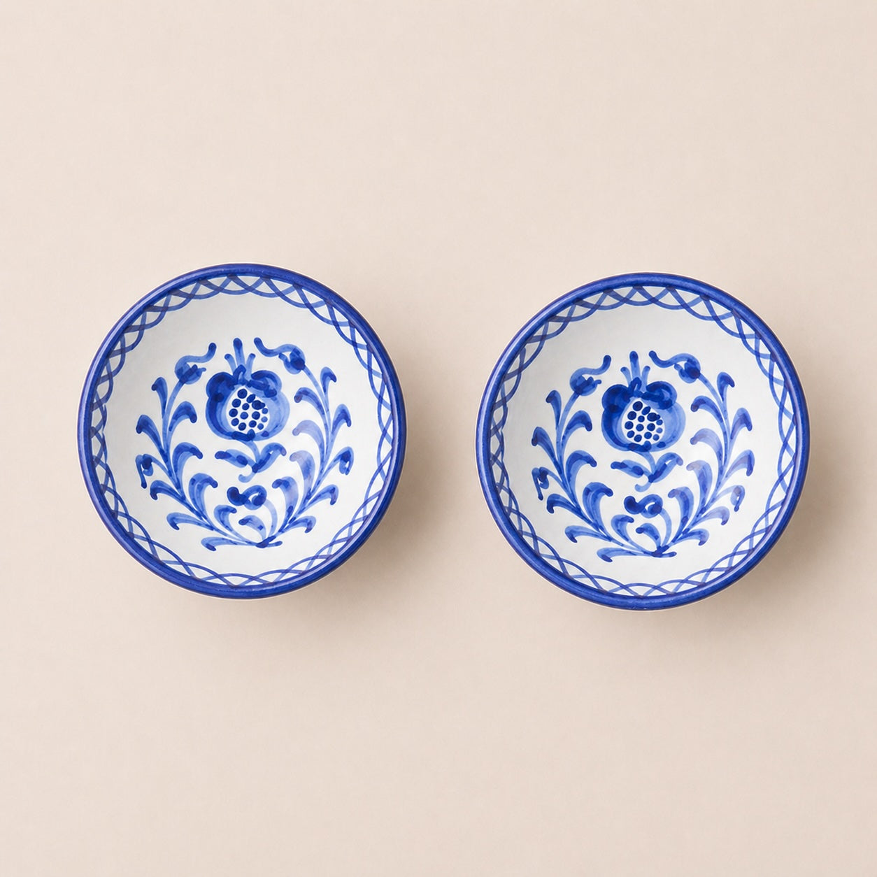 Two blue and white ceramic bowls with floral patterns on a beige background