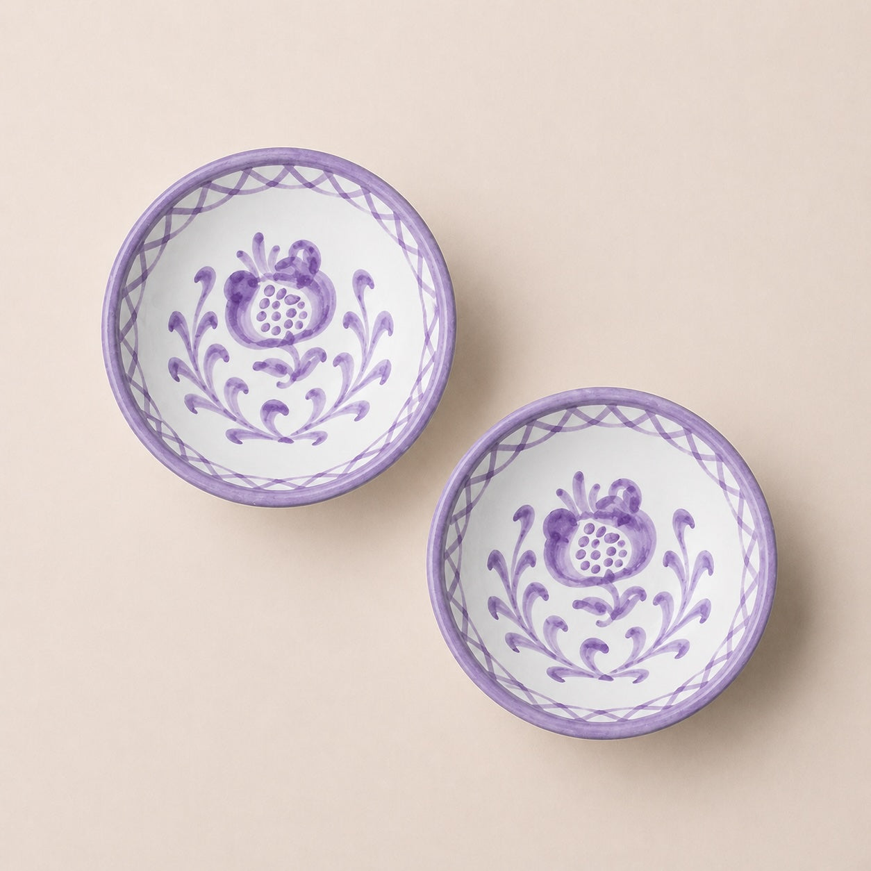 Two ceramic bowls with purple floral patterns on a beige background
