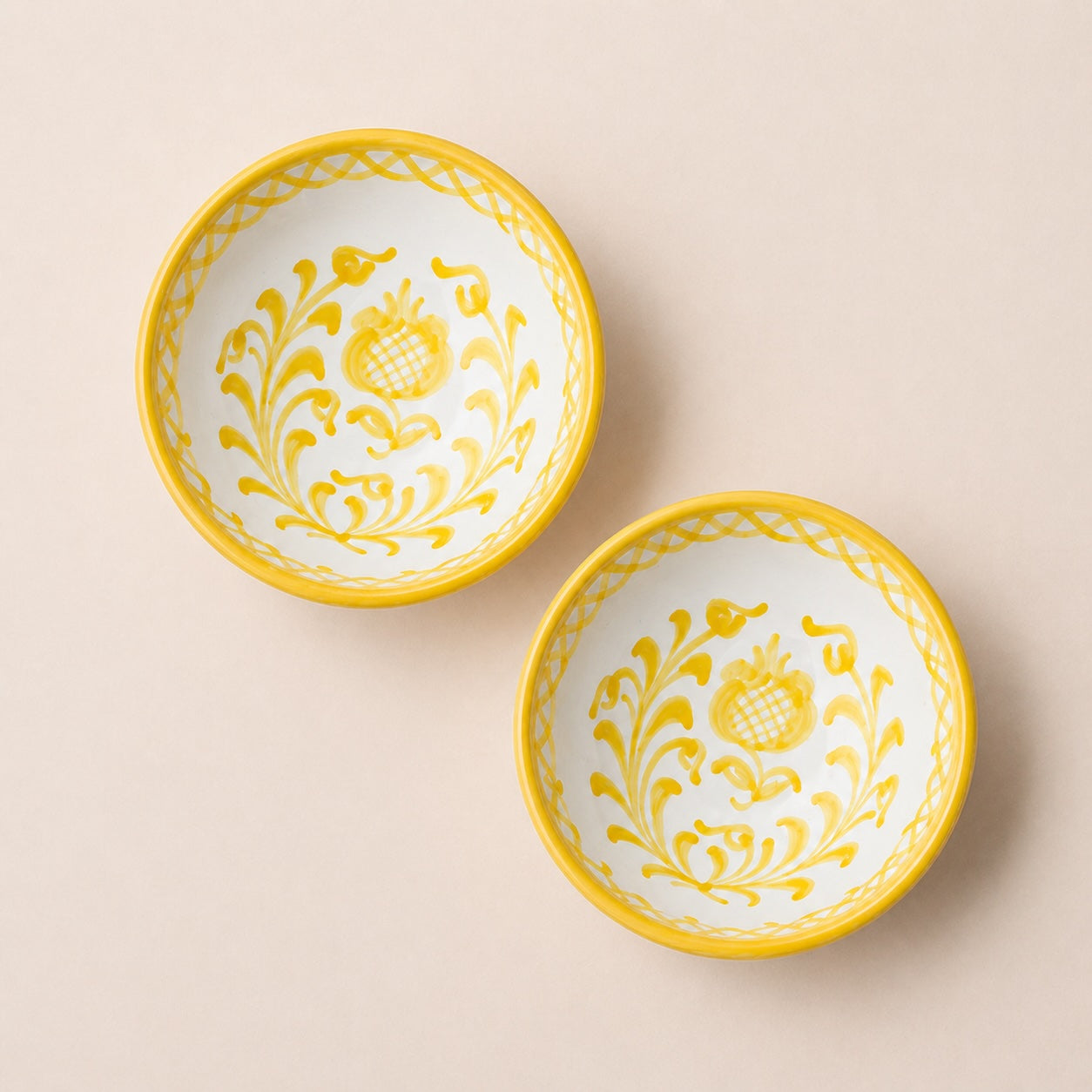Two yellow-trimmed ceramic bowls with floral patterns on a beige background